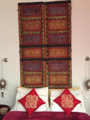 a bedroom with a bed with red pillows and a wall at Riad Laly Tourisme Eclairé Le bijou de la medina in Marrakesh