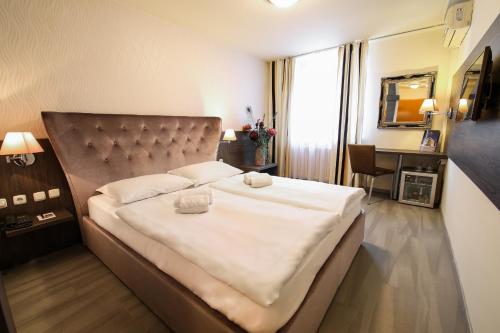 a bedroom with a large white bed with white sheets at Hotel Evropa in Celje
