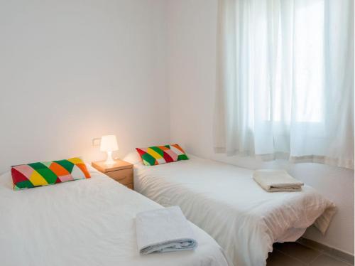 2 camas en una habitación blanca con ventana en Apartment Almadraba, en Rota