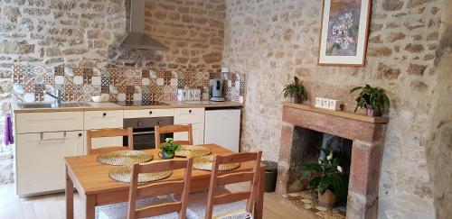 une cuisine avec une table et des chaises ainsi qu'une cheminée dans l'établissement De La Terre Farm Stay, à Lignieres-Orgeres