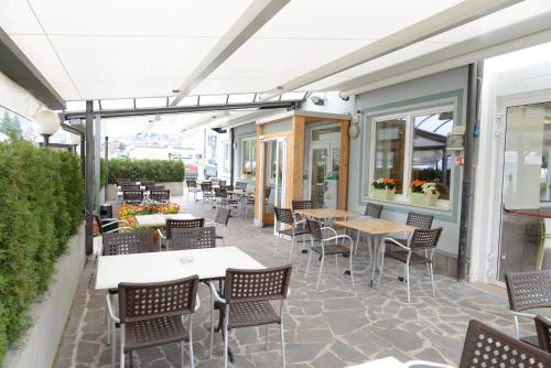 a dining area with tables, chairs, and umbrellas at Al Brenta in Levico Terme