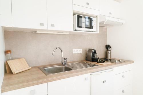 a kitchen with white cabinets and a sink at LOVELY PARIS - 6 Pers - Wifi in Chatou