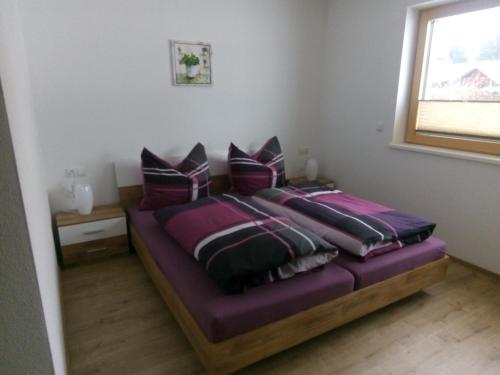 - une chambre avec 2 lits avec des draps violets et une fenêtre dans l'établissement Barschtlerhof, à Axams