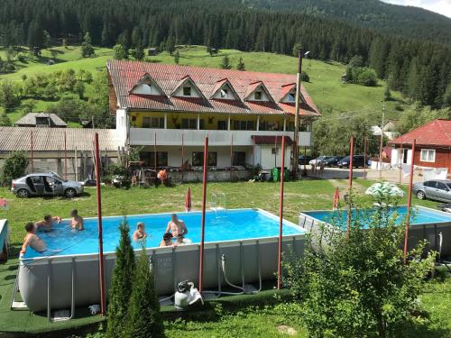 eine Gruppe von Menschen in einem Pool vor einem Haus in der Unterkunft Pensiunea Serbeca in Broşteni