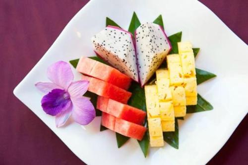 a white plate with fruit and vegetables on it at Authentic Cambodian Angkor Cottage in Siem Reap