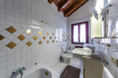 e bagno con vasca, servizi igienici e lavandino. di Novalesi Red House a Noale