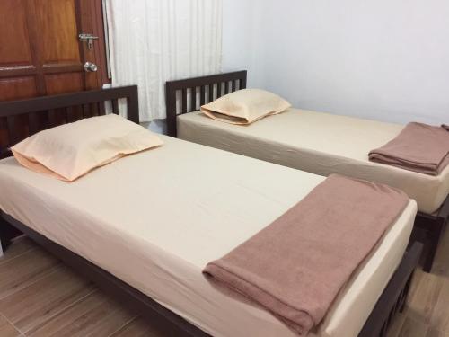 Dos camas en una habitación con toallas encima. en Siriwal Guesthouse, en Phra Nakhon Si Ayutthaya