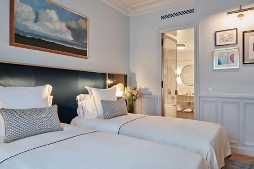 two white beds in a room with a painting at Grand Powers Hotel in Paris