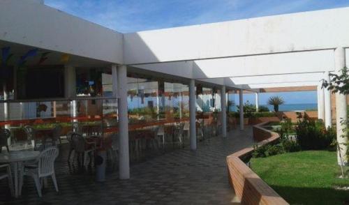 an outdoor patio with tables and chairs and a restaurant at BEIRA MAR DE JATIÚCA in Maceió