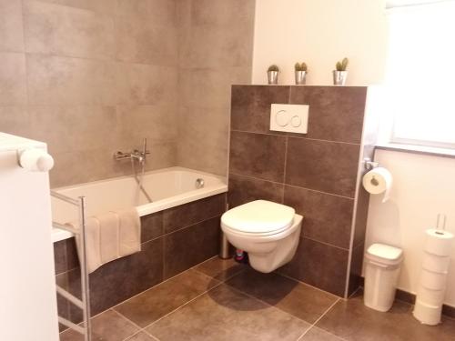 ein Badezimmer mit einem WC und einer Badewanne in der Unterkunft WELCOME B&B in Weismes