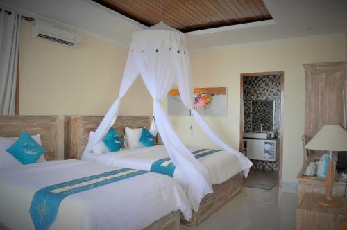 a bedroom with two beds with mosquito nets at Ocean Terrace Suite And Spa Luxury in Nusa Penida