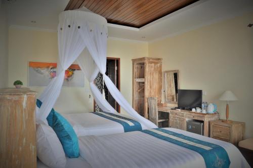 a bedroom with two beds and a television in it at Ocean Terrace Suite And Spa Luxury in Nusa Penida