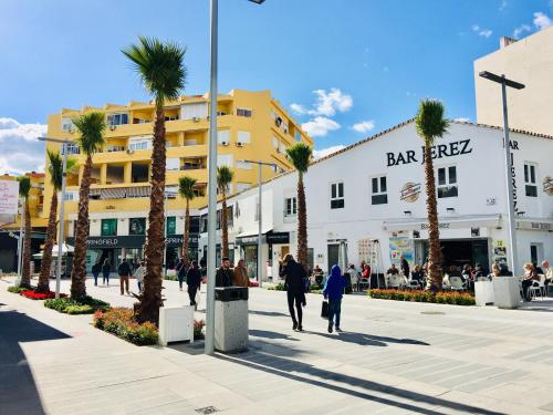a group of people walking down a street with palm trees at New Central Studio Torremolinos in Torremolinos