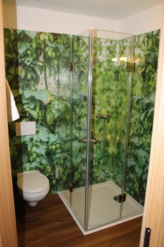 a bathroom with a shower with a toilet and plants at Hotel Brauereigasthof Amberger in Kösching