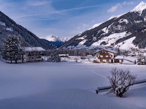 a house in the snow with mountains in the background at Haus Marianne in Sankt Jakob in Defereggen