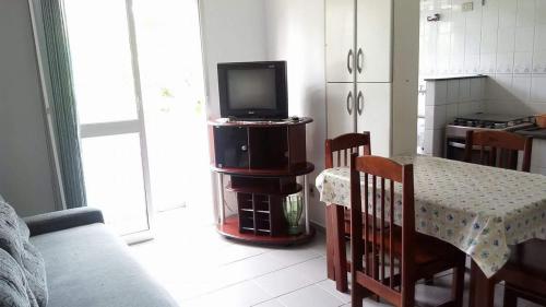 a kitchen with a table and a television on a cabinet at Ubatuba Apartamento Maurilio in Ubatuba