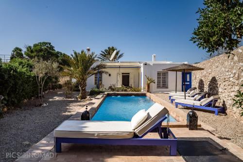 a swimming pool with lounge chairs and a house at Dar Mayssoun in Ghazoua