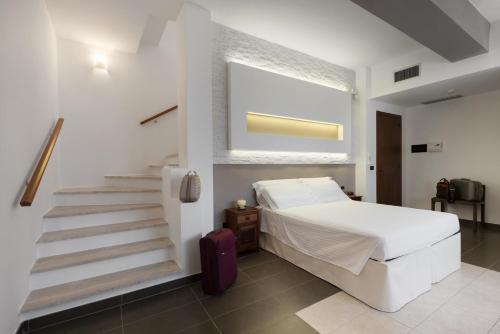 een slaapkamer met een wit bed en een trap bij La Chiocciola in Castrignano del Capo