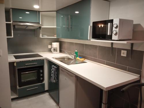 a kitchen with a sink and a microwave at l'essentiel in Ault