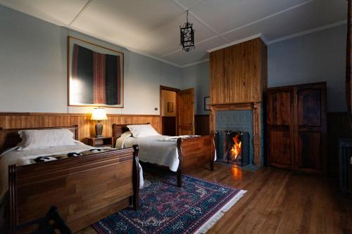 a bedroom with two beds and a fireplace at Hotel Estancia Caleta Josefina in Onaisin