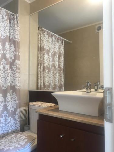 a bathroom with a sink and a toilet and a mirror at Departamento 606 in Temuco