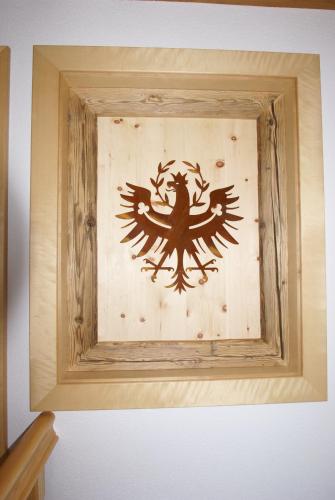 a wooden picture frame with a bird design on a wall at Ferienwohnung Bergheim in Fügenberg