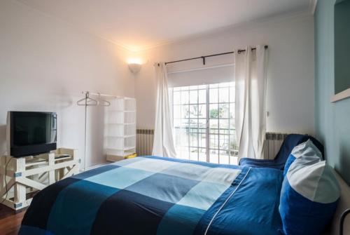 ein Schlafzimmer mit einem blauen Bett und einem Fenster in der Unterkunft Leiria Fatima Nazaré 3 Bedroom House in Leiria