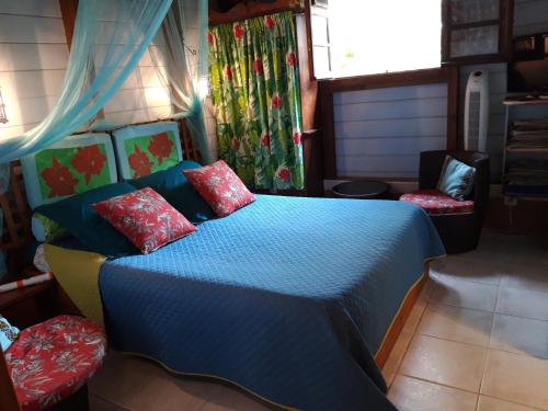 a bedroom with a blue bed with red pillows at Les Fougères in Baie-Mahault