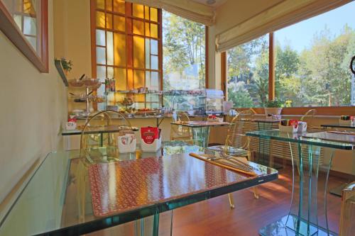 un restaurante con mesas de cristal, sillas y ventanas en Il Giardino Di Albaro, en Génova