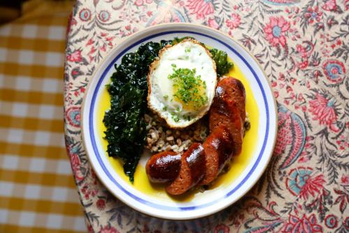 a plate of food with sausage and greens on a table at Hotel Peter and Paul, an Ash Hotel in New Orleans