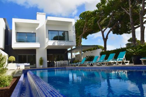 a villa with a swimming pool in front of a house at Amora Villa - Vilamoura in Vilamoura
