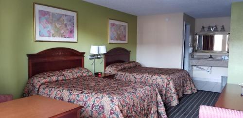 Cette chambre comprend 2 lits et une table. dans l'établissement Newport News Inn, à Newport News