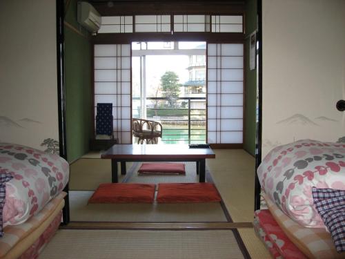 a room with two beds and a table and a window at Ryokan Nakaya in Hamamatsu
