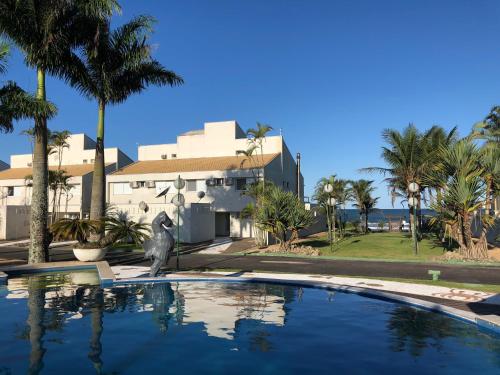 a swimming pool in front of a house with palm trees at Casa Beira Mar com 5 suites in Itapoa