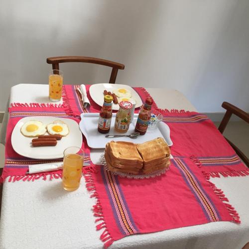 a table with a breakfast of eggs sausage and bread at White Lodge in Kandy