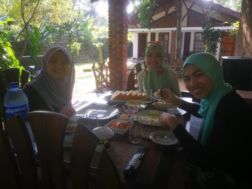 three women sitting around a table eating food at Green Cottage in Anuradhapura