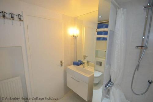 a white bathroom with a sink and a shower at Tackleway Cottage in Hastings