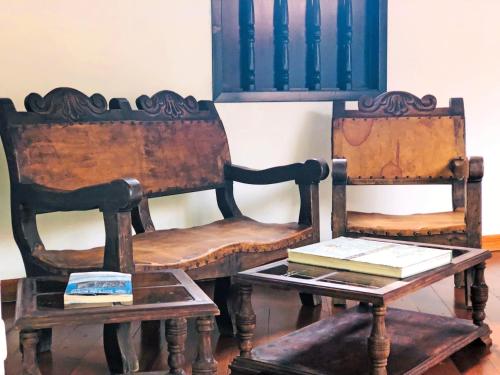 Dos sillas de madera y una mesa con un libro. en Hotel San Gabriel, en El Cocuy