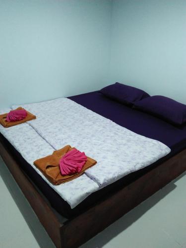 a bed with two towels on top of it at Wattana Home in Thong Pha Phum