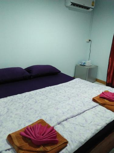 łóżko z dwoma różowymi ręcznikami na górze w obiekcie Wattana Home w mieście Thong Pha Phum
