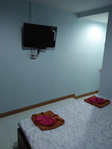 een slaapkamer met een bed en 2 badjassen bij Wattana Home in Thong Pha Phum