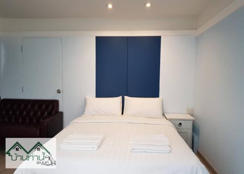 a bedroom with a bed with white sheets and a chair at Baanthanam Nont in Nonthaburi