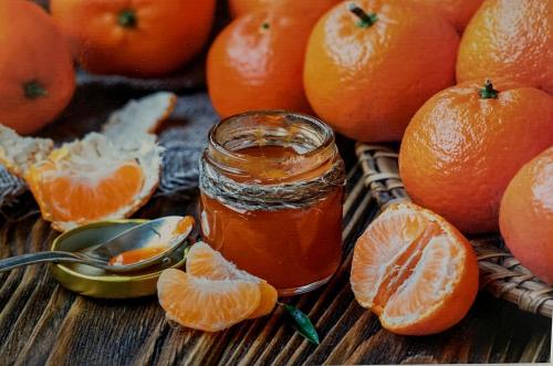 a jar of orange jam next to a pile of oranges at Le Maestranze Deluxe Rooms in Sciacca