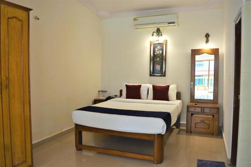 a bedroom with a white bed and a mirror at Sonika's Paradise (Studio) in Candolim