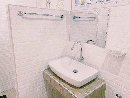a white bathroom with a sink and a mirror at RiverTree House in Nong Khai