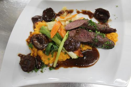 a white plate of food with meat and vegetables at Hotel Brauereigasthof Amberger in Kösching