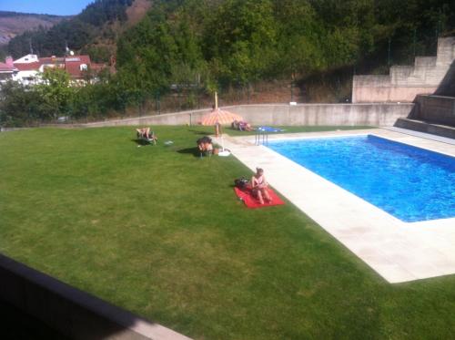 un grupo de personas sentadas en un césped junto a una piscina en apartamento el mirador en Ezcaray