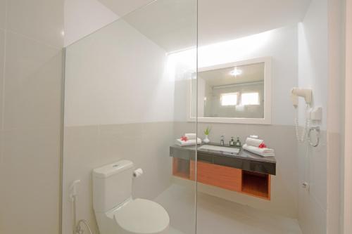 a white bathroom with a toilet and a sink at Equator Village Maldives in Gan