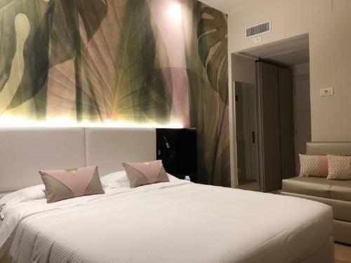 a bedroom with a large white bed with pink pillows at Hotel Ariston & Apartments in Varazze