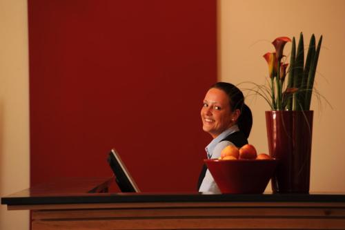 a woman sitting at a desk with a bowl of oranges at Park-Hotel Hübner in Warnemünde